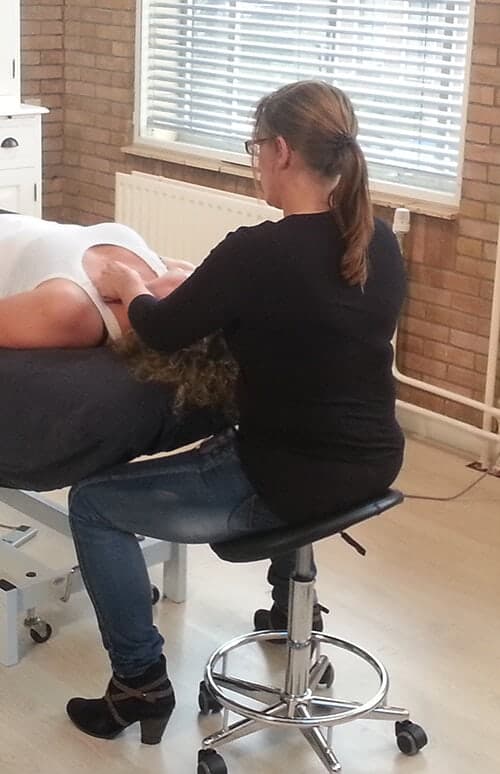 Hanneke Schuiling masseert de nek van een cliënte op de behandeltafel