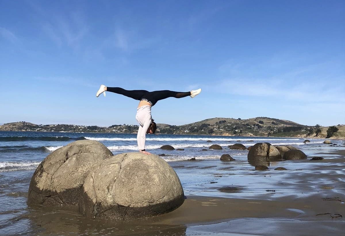 Een handstand op een ronde kei aan zee