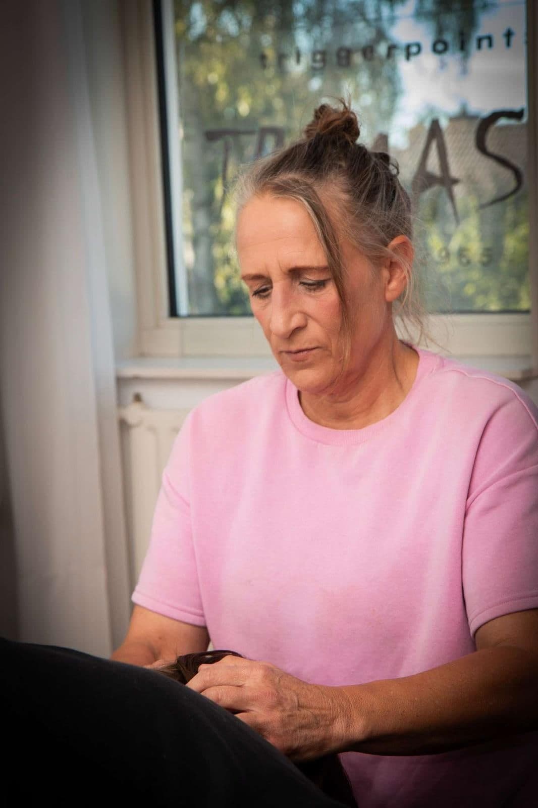 Hanneke Schuiling geconcentreerd aan het werk in haar praktijk, met TRIMAS op het raam